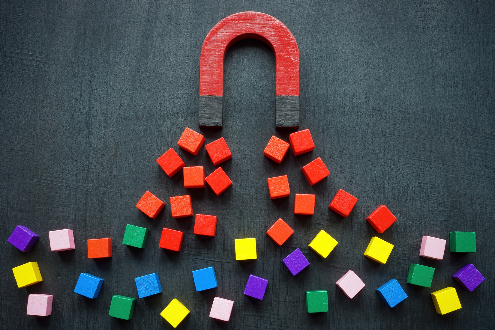The magnet attracts colored cubes. Leads generation and acquisition concept.
